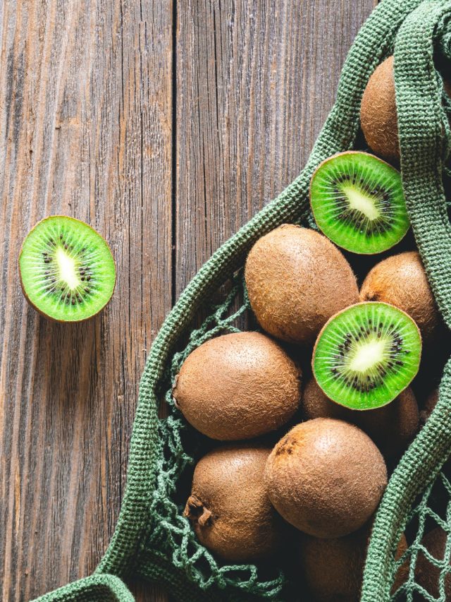 Fruits of kiwi in a mesh bag on a wooden background, top view, rustic style,